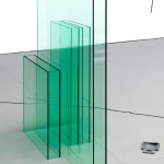 green plexiglass sculptural formations aligned closely next to each other, each one resembling a thin rectangular box-like shape.