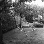 A sculpture of pieces of rope hanging from a string suspended over the ground outdoors.