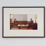 A framed image of two men sitting on either side of a green sofa.