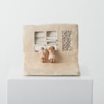 small ceramic piece depicting two figures peeking into a window in a building facade