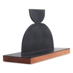Scott Albrecht steel sculpture - two semi circles, smaller one balanced on larger one. Wood base - side view