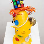 yellow lamp with dog facial features with various items stacked on top also with dog faces