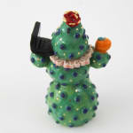 Jen Dwyer sculpture - green cactus figure with one eyeball at center holding a laptop and other accessories