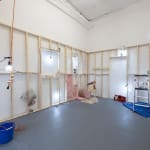 room with white walls and wooden scafolding with various dog human sculptures displayed in different scenes