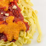 Glass sculpture of a white plate with spaghetti topped with dino nuggets