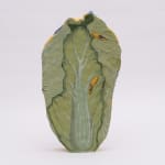 Flat sculpture of a cabbage with a painting of a table with a plate of vegetables, a crab and a lobster on a blue and white checkered table clothe. On the side of the sculpture is yellow with fruit and vegetable stickers. On the back is a realistic painting of a green cabbage
