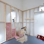 white room with wooden scaffolding with dog human sculptures displayed in various scenes