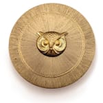gold circular cosmetic case with gold owl face in centere