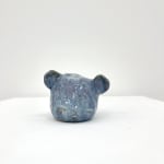 Ceramic sculpture of a bears head with its eyes closed in a blue purple glaze