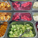 Painting of a buffet counter full of different foods in metal tins.