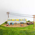 miniature diorama by Abigail Goldman of woman being roasted over an open flame in front of an RV