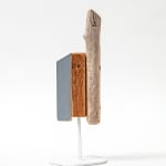 Wooden sculpture with a piece of drift wood and two other flat pieces of wood side by side on a metal stand by Hyland Mather