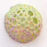 A sculpture by Dan Lam of a sphere with round holes broken through out the top of it.