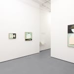 white gallery wall with four paintings in blue, black, and warm tones