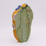 Flat sculpture of a cabbage with a painting of a table with a plate of vegetables, a crab and a lobster on a blue and white checkered table clothe. On the side of the sculpture is yellow with fruit and vegetable stickers. On the back is a realistic painting of a green cabbage