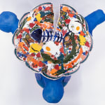 Sculpture of three blue birds holding a plate of food and various things on their backs
