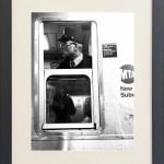 black and white photo of subway train conductor looking out window in black frame