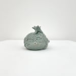 Ceramic sculpture of a head with its eyes closed and a star on top of its head in a light green glaze