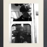 black and white photo of subway train conductor looking out the window in black frame