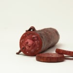 Stephen Morris "Salami" ceramic sculpture of realistic red salami with two pieces cut out revealing a face