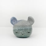 Ceramic sculpture of a bear head with striped blue tones across its head.
