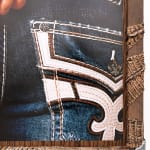 Photo of a persons back with embroidered jeans and black longsleeve shirt with their hands behind their back
