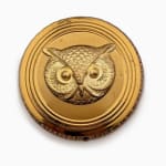 gold circular cosmetic compact with a large owl face in the center