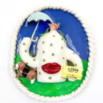 Sculpture of a creature with large red lips holding an umbrella and a box with a dog next to it