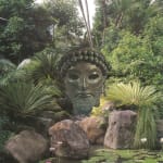borwn bust/statue head surrounded by a green landscape
