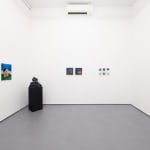 white gallery walls with paintings of various sizes and a black pedestal with a sculpture in the corner