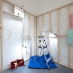 white walls with wooden scaffolding and dog human sculptures displayed in various scenes