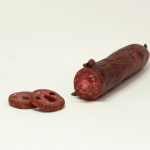 Stephen Morris "Salami" ceramic sculpture of realistic red salami with two pieces cut out revealing a face