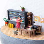 miniature diorama by Abigail Goldman of a woman holding a shotgun in an office and a bleeding man bent over a desk