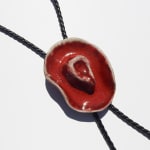 Ceramic bolo tie of a red cowboy hat on a black leather tie