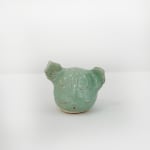 Ceramic sculpture of a the artists dog head in a mint green glaze
