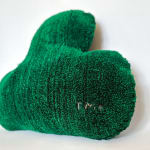 Side view of soft sculpture of a dark green leaf