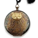 Round cosmetic compact with gold owl face and black tassel