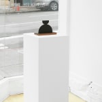 Scott Albrecht steel sculpture - two semi circles, larger one balanced on smaller one. Wood base - side view