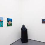 white gallery walls with paintings og various sizes and colors, and a black pedastal with a house sculpture