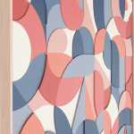 pink, blue, and white wooden relief piece featuring many smaller pieces in a light wood frame side angle