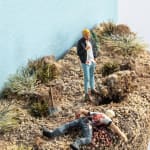 mini scene of a man killing another in a desert like landscape