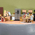 woman sitting in kitchen with a pile of amazon boxes, some containing bloody body parts