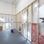room with white walls and wooden scaffolding with dog human cultures displayed in various scenes such as riding a drill
