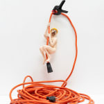 nude anthropomorphic dog hanging from orange extension cord