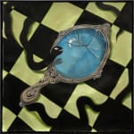 framed Minyoung Kim painting of black snake looking into broken hand mirror that is reflecting a crescent moon. Black and green checkered tile floor background