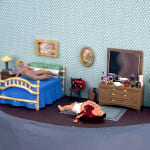 naked woman laying on bed while a man is bleeding from the chest on the floor