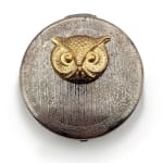 Silver circular cosmetic compact with gold owl face
