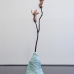 Sculpture of two-pronged twig emerges from blue mountain peak. From each end of the twig protrudes a flower of human hair, skin tongues and tentacles.