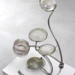 Winding aluminum tube sculpture which holds five different resin lenses. Each lens is created from the cast of the artist’s shaved head and butt and are protruding out at different heights