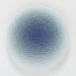 Layers of multi-colored threads strung across a round wooden and plaster panel create the effect of a tight dark blue center that fades to pastel blue on the outer border